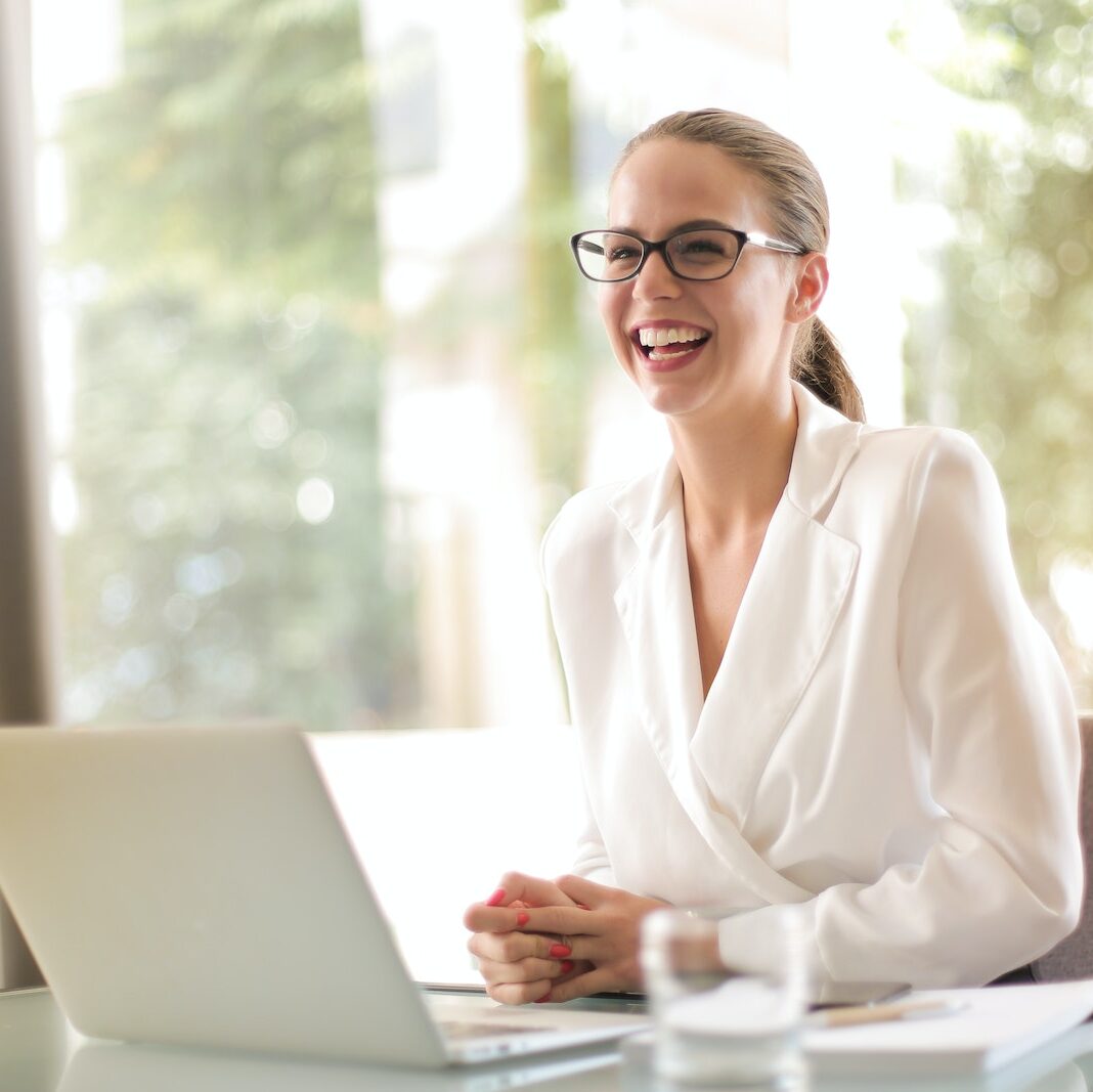 Laughing businesswoman working in office with laptop
