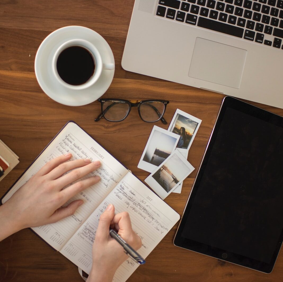 person holding ballpoint pen writing on notebook